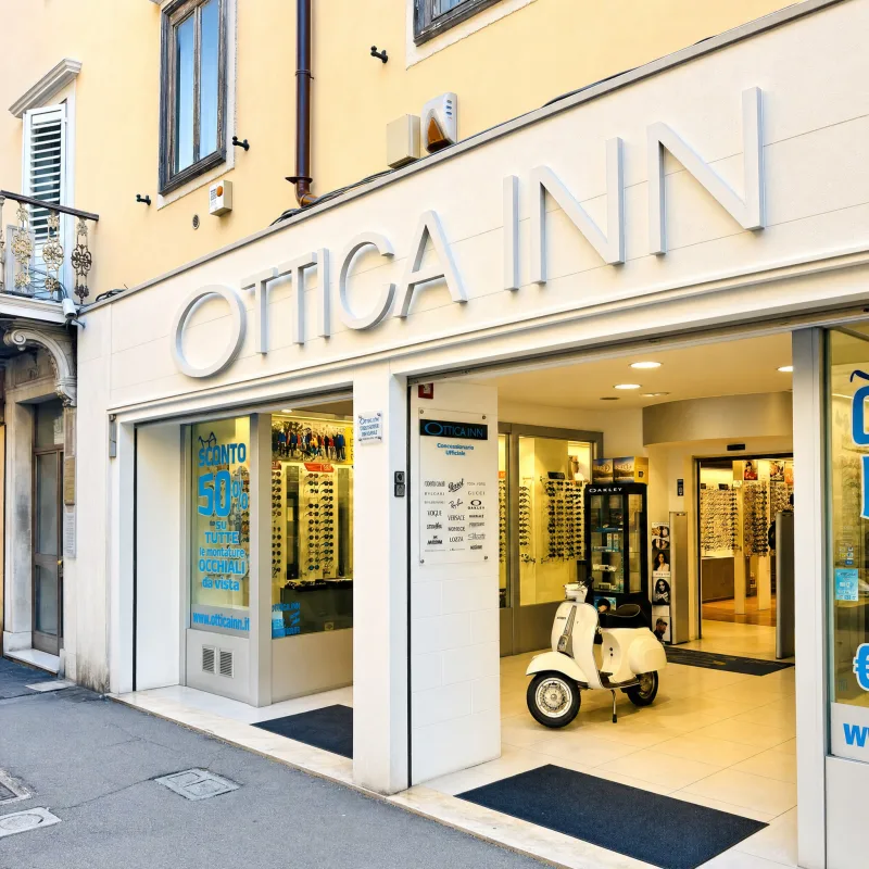 Vetrina Ottica Inn Via Roma 3 Trieste con insegna grande e Vespa